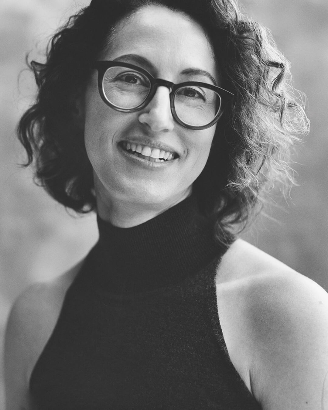Black and white portrait of a person wearing glasses and a turtleneck.