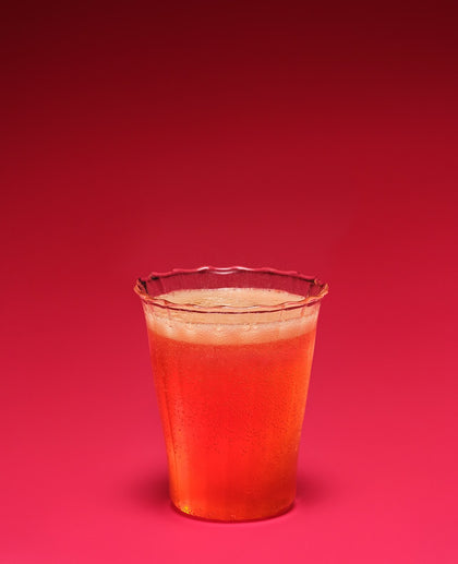 Clear plastic cup with red liquid on a red background