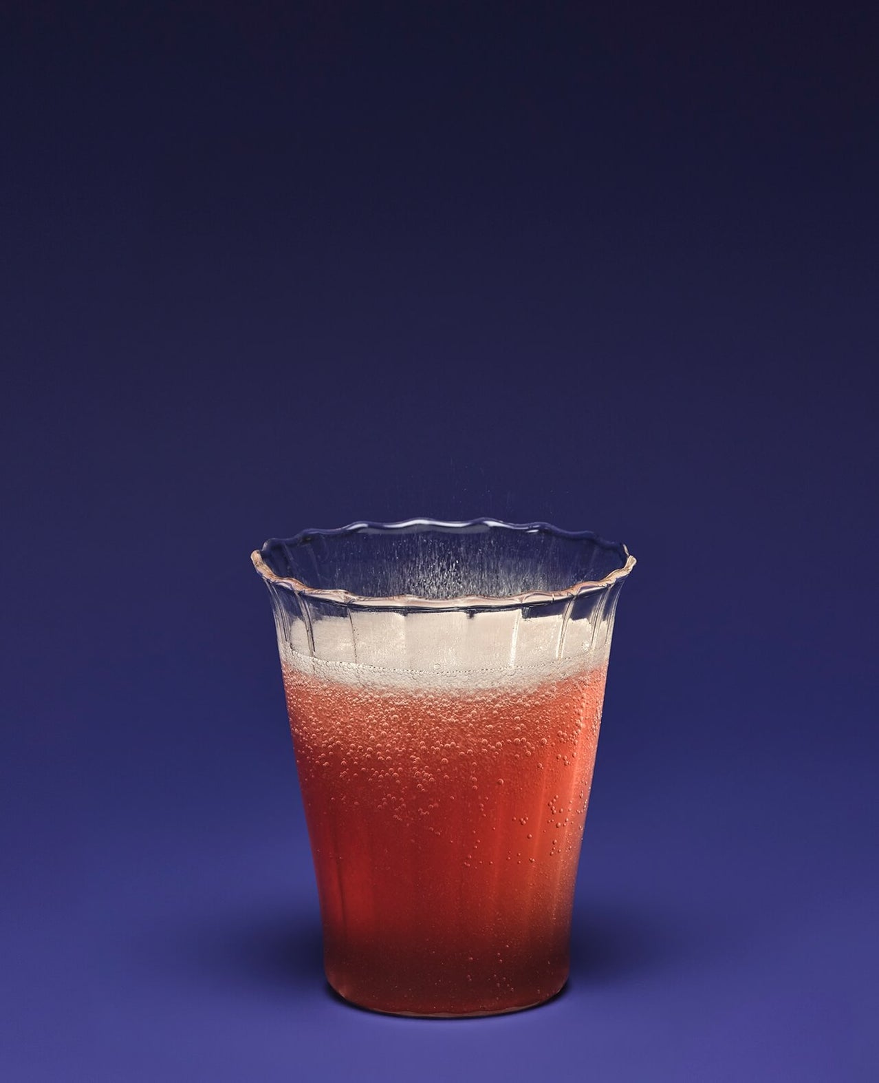 Clear glass with red liquid on a blue background