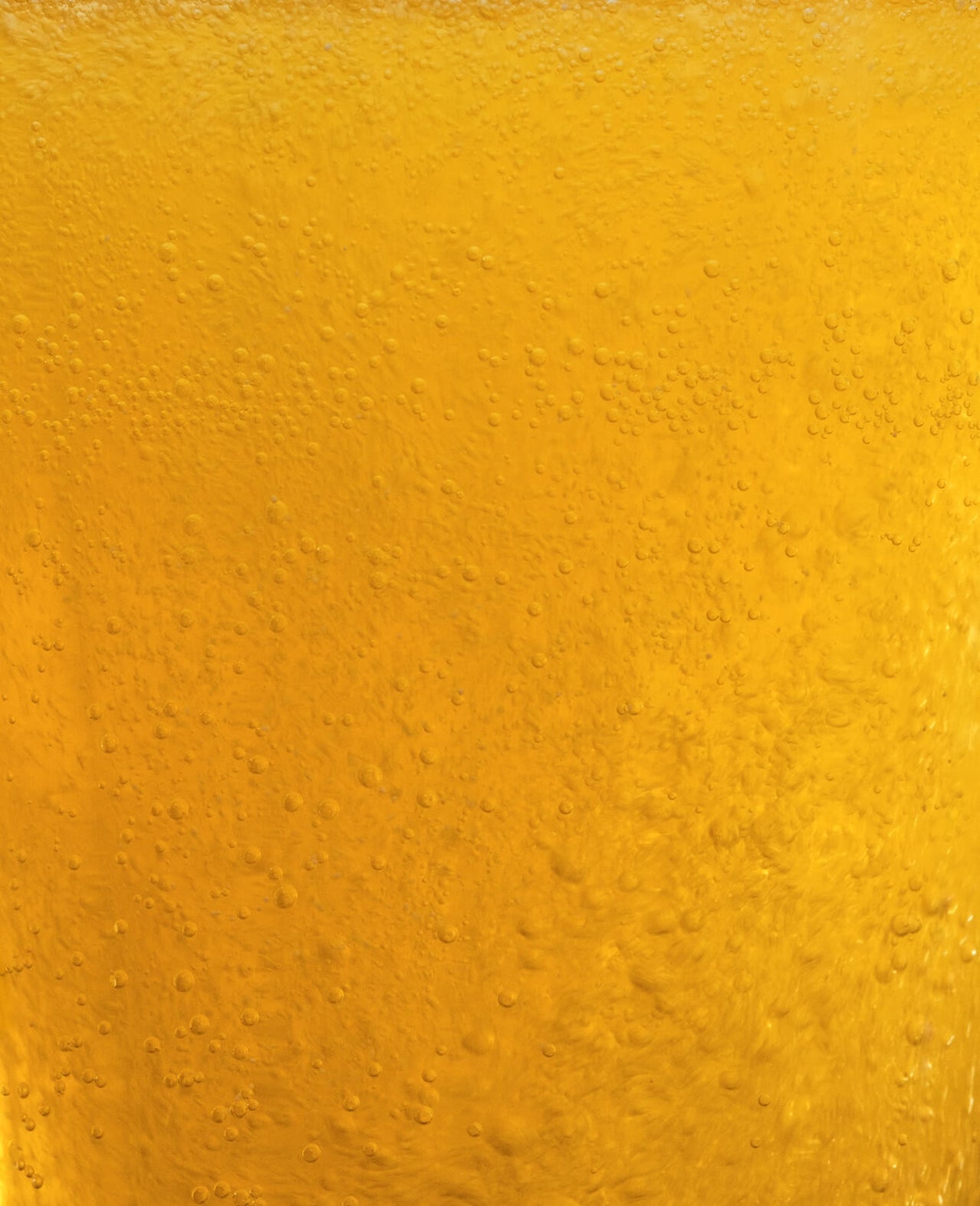 Close-up of golden yellow liquid with bubbles rising through it.