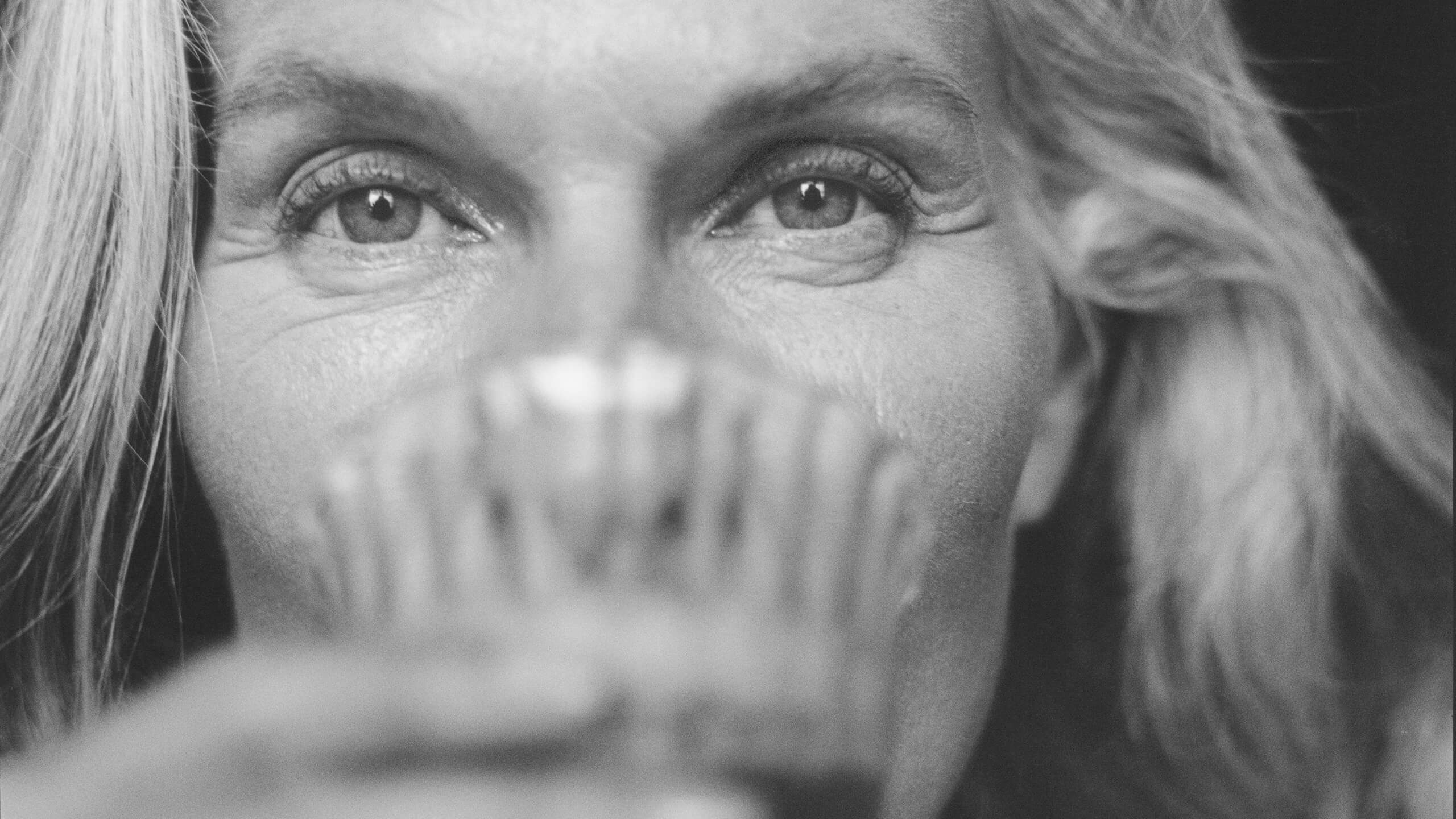 Black and white close-up of a woman's face with a blurred area over her mouth.