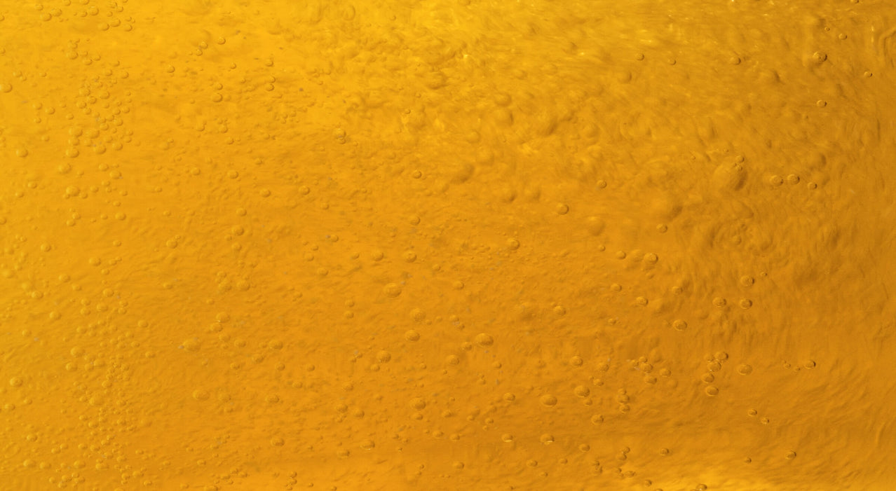 Close-up of golden yellow liquid with bubbles rising through it.