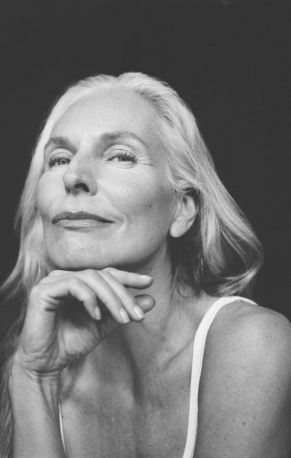 Black and white portrait of a woman with her hand on her chin against a dark background